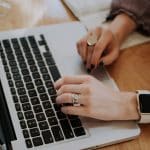 Picture of a woman typing on a laptop. Image is being used for blog post titled, Build Brand Awareness With Press Release Distribution