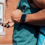 Picture of a man in a blue shirt wearing fitness gear, reading his mobile phone. Image is used for blog titled, "Newswire Helps Land Wall Street Journal Feature for Tech Industry Client"