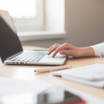 Image of a woman in a white shirt who has her hand on a laptop. Image being used for a blog about press release distribution benefiting companies of all industries.