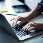 Picture of a woman's hands typing on a Mac. Image is being used for a Newswire blog post that provides seven press release writing tips.