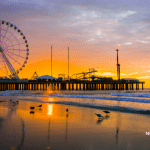 Picture of the Steel Pier in Atlantic City, New Jersey at sunset. Birds are on the shoreline. This image is being used for a blog post about the top media outlets in New Jersey.