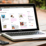 Picture of a MacBook on an outdoor table. On the screen is an example of Newswire's Media Room.