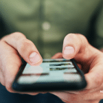 Picture of a guy holding a smart phone looking at the internet. Image is being used for a Newswire blog post about the important of press release distribution in the age of social media.