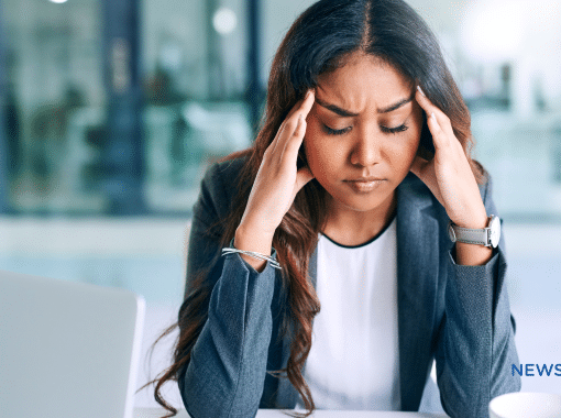 Picture of a business woman with dark complexion looking stressed and holding her hands at her temples. This image is being used for a blog about the use of media monitoring for crisis management.