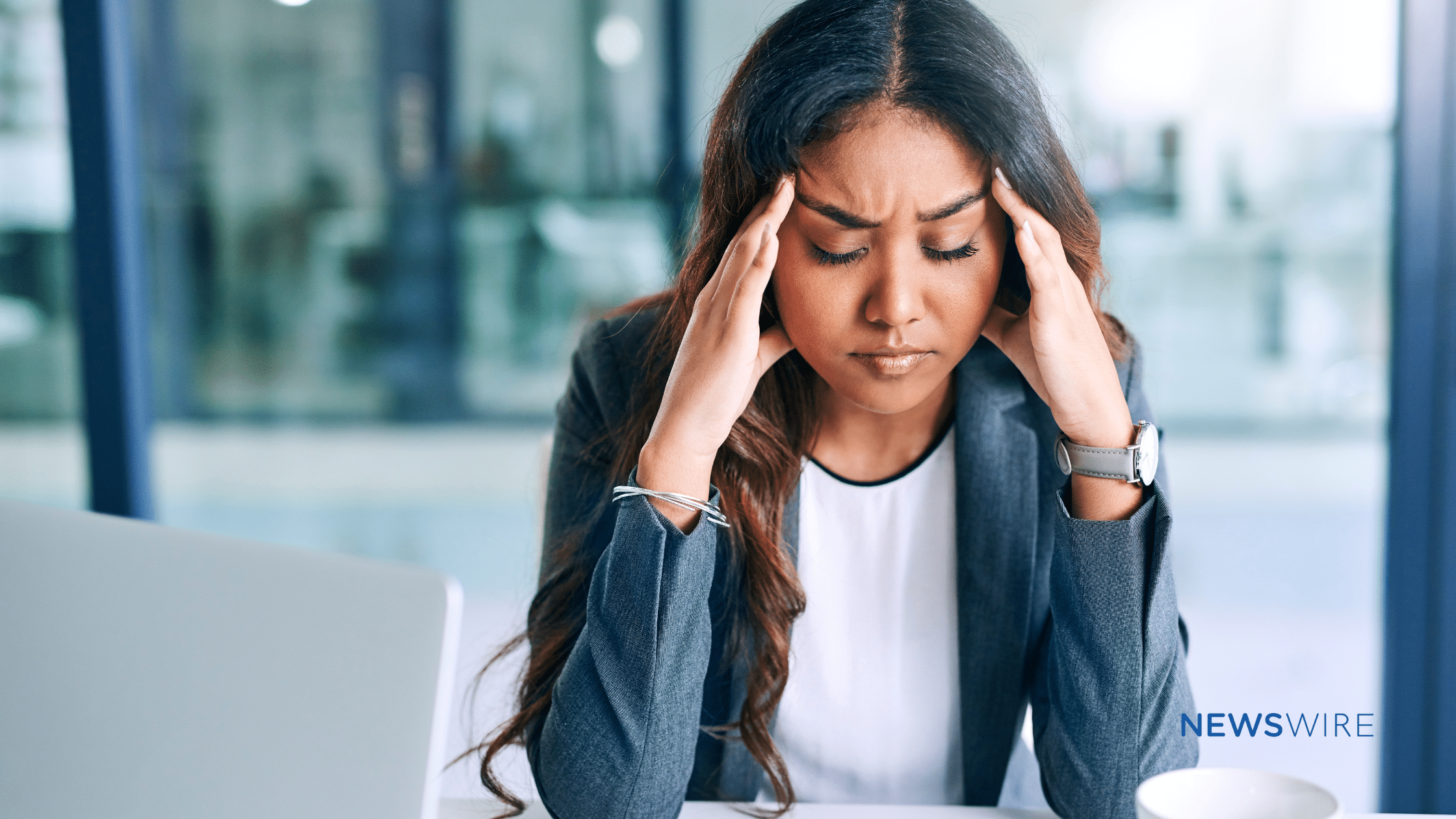 Picture of a business woman with dark complexion looking stressed and holding her hands at her temples. This image is being used for a blog about the use of media monitoring for crisis management.