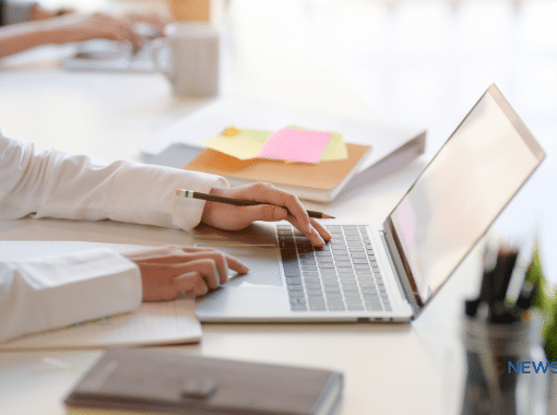 Picture of a lady's hands on a MacBook in a business setting.