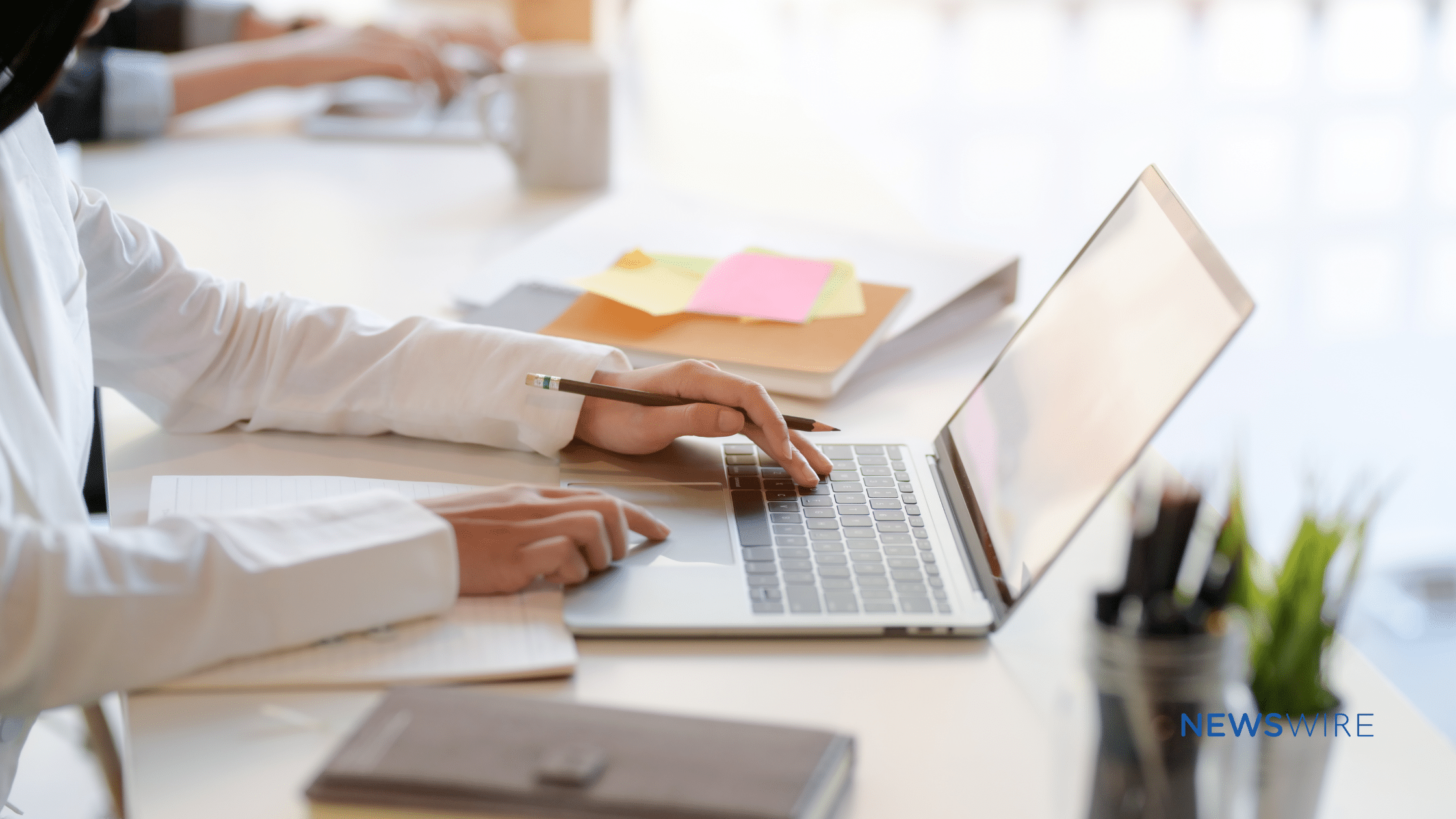 Picture of a lady's hands on a MacBook in a business setting.