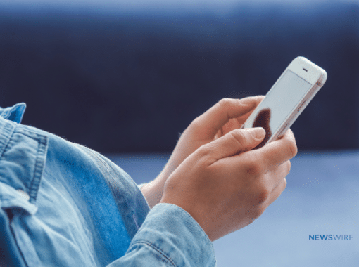 Close-up picture of a lady in a jean shirt holding a smart phone in both hands.