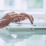 Picture of a woman's hands typing on a laptop.