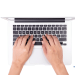 Picture of a woman's hands typing on a Macbook.